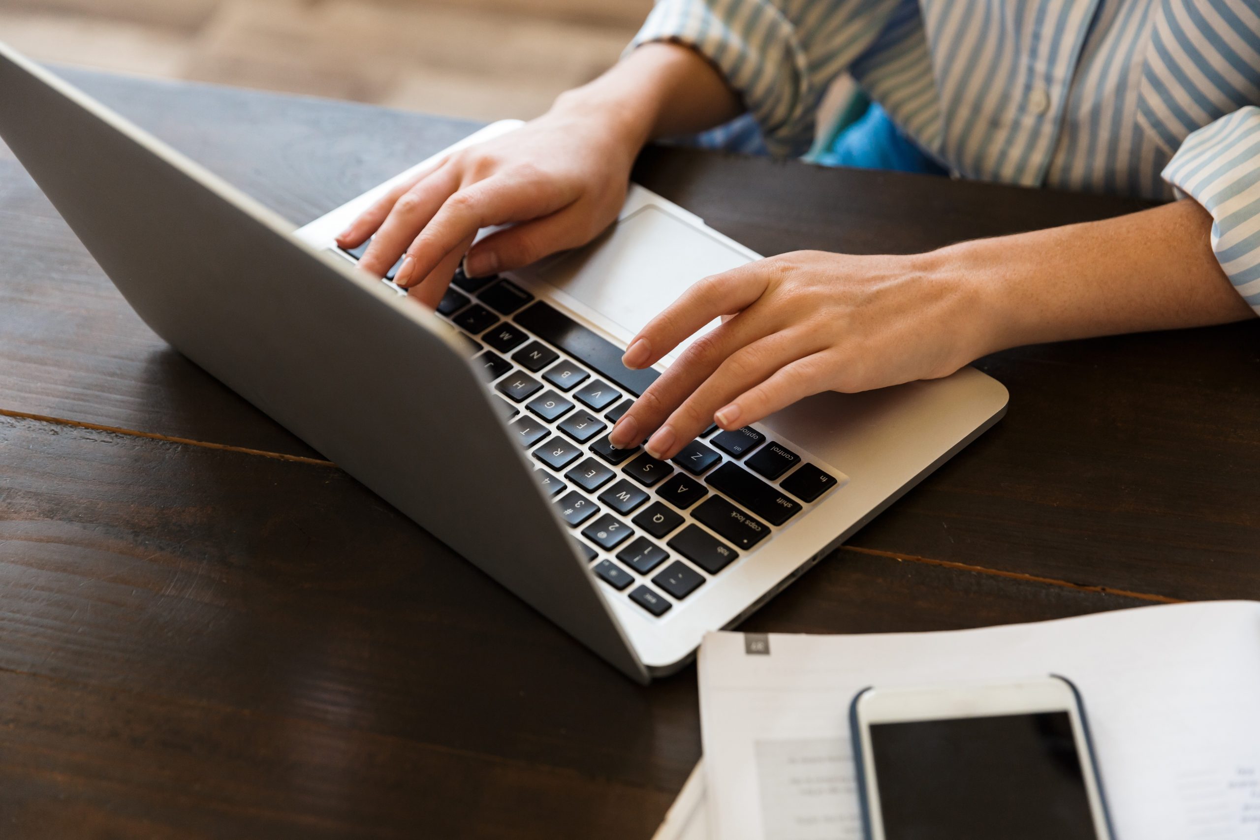 Person working at a laptop with paperwork